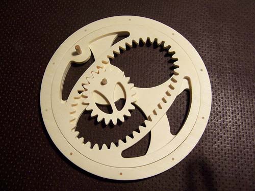 A close-up photograph of a white plastic gear with teeth against a black background.
