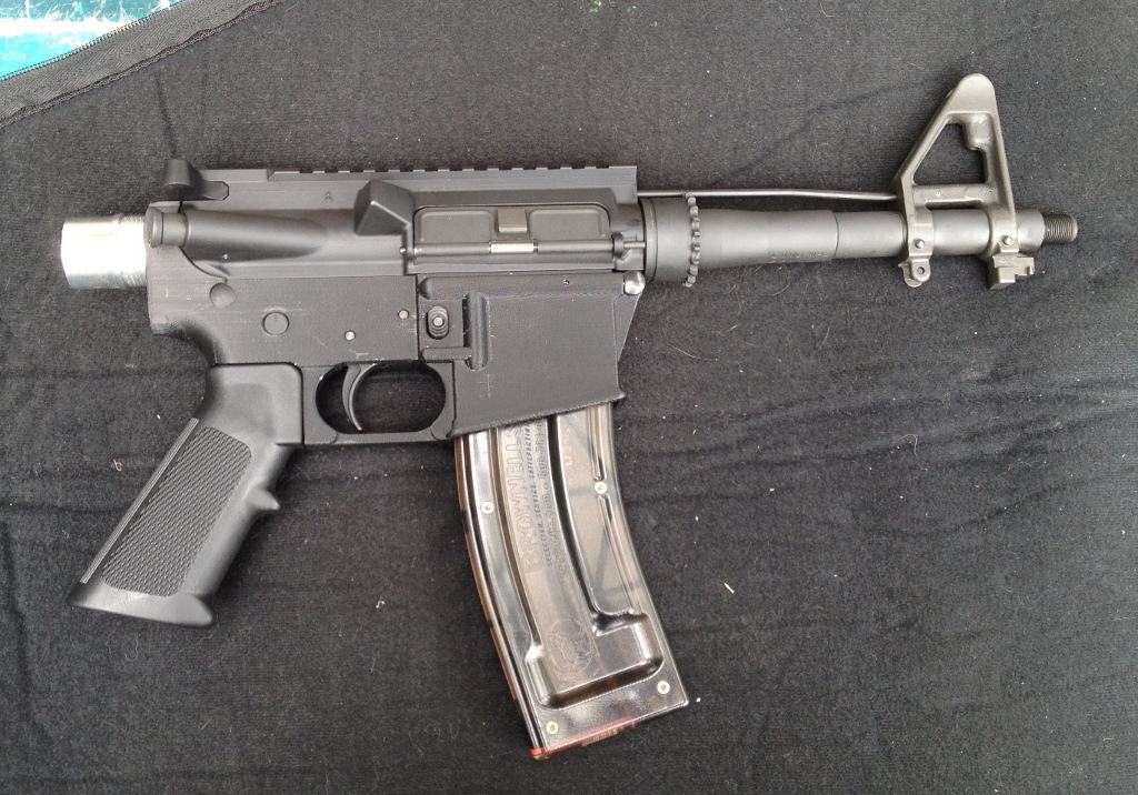 Black semi-automatic rifle with curved shape and metal barrel.