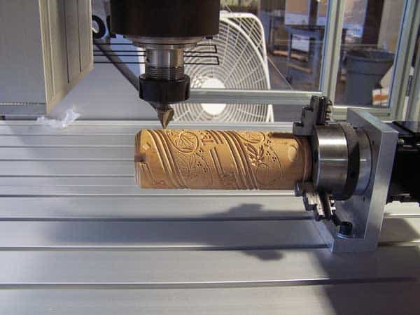 A large CNC milling machine with 4th axis rotary table and wooden workpiece clamped on top.