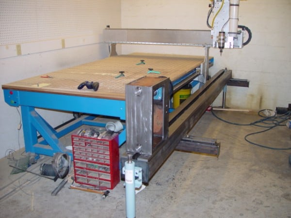 Large blue metal frame supporting a wooden worktable with grid pattern and various tools.