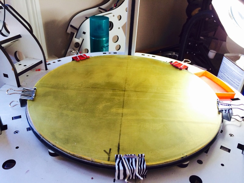 Yellow material clamped to white table using clips, secured with black tape.
