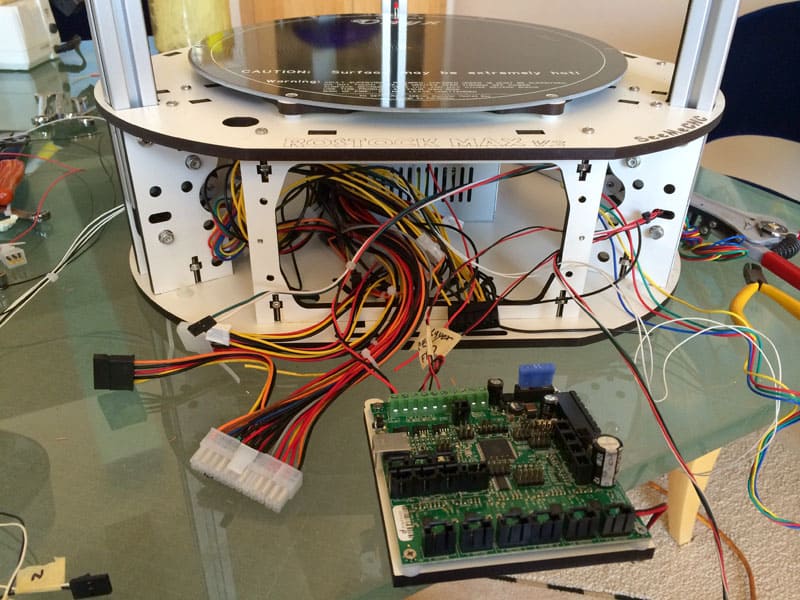 Three-dimensional printer wiring system with intricate network of cables and wires.