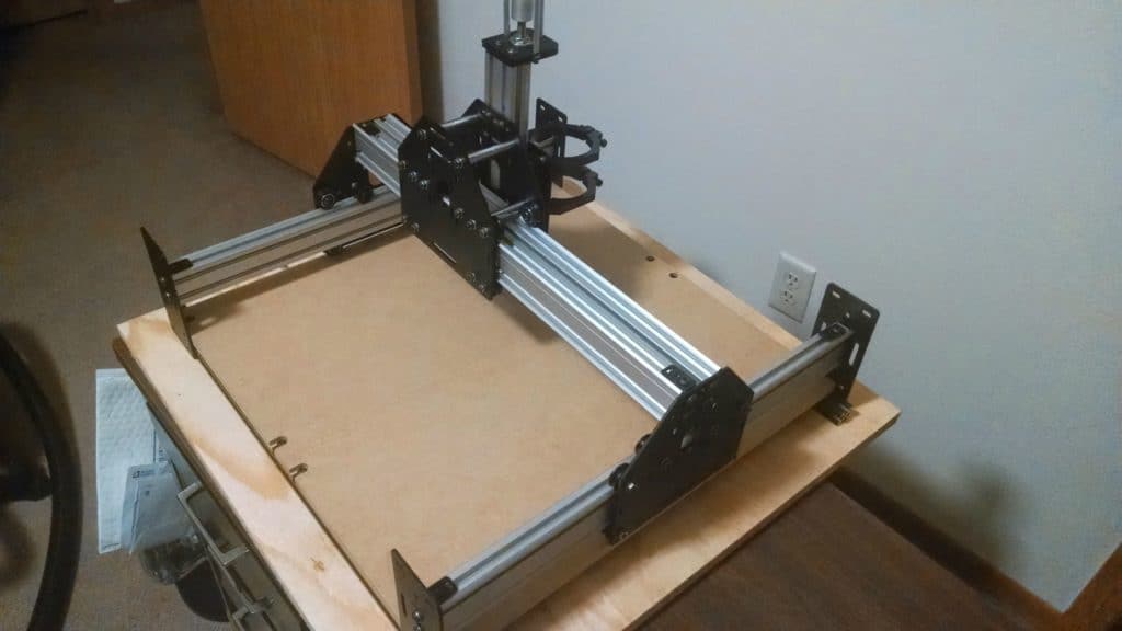 Wooden platform with metal frame and machine on top, beige carpeted floor, white wall background.
