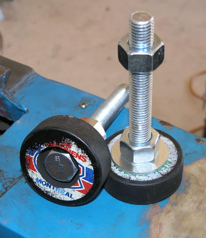 Two hockey pucks with bolts through them on a blue surface.