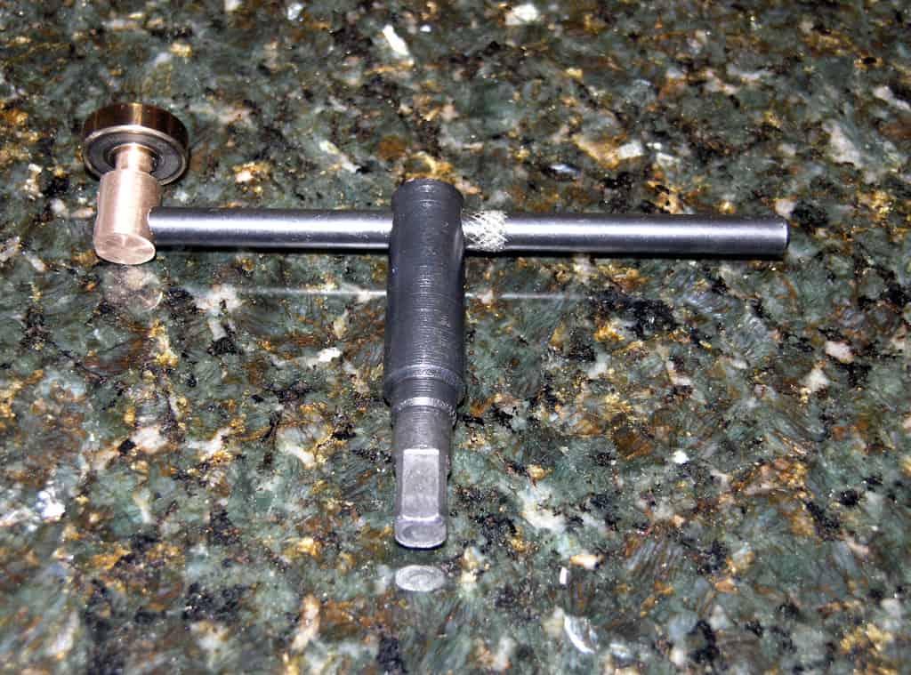 T-shaped hand tool with long metal rod.