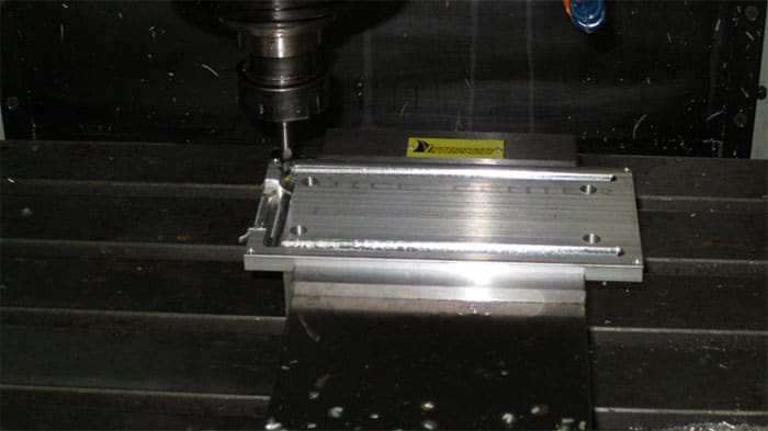 Metalwork machine tool with silver plate and yellow sticker on a black background.