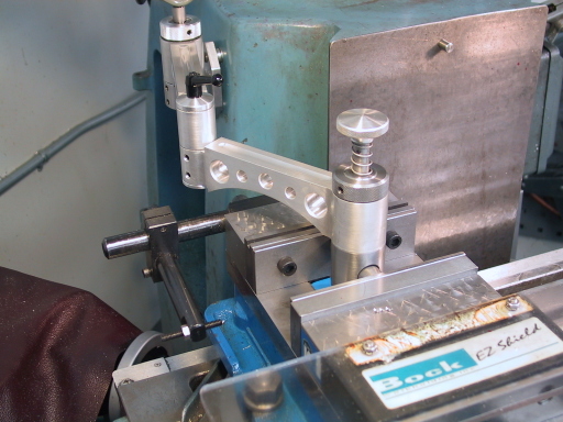 Mill vise swing arm with silver arm and blue handle attached to machinery.