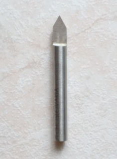 Silver metal V-bit with sharp point.