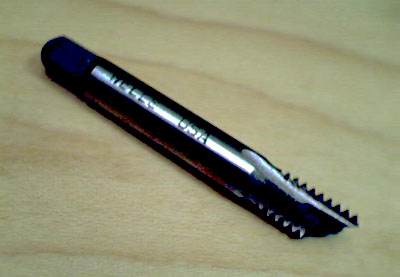 A close-up photograph of a broken tap with tapered shank and cutting edge.