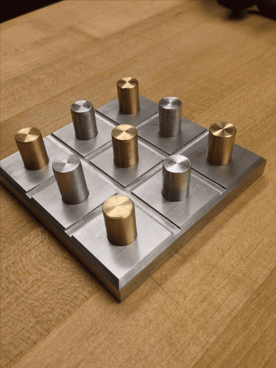 Metal plate with 9 cylindrical protrusions in a 3x3 grid, varying heights, made of brass and steel.