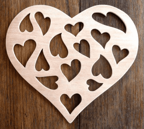 Light-colored wooden heart with cut-out design of smaller hearts against dark wood background.