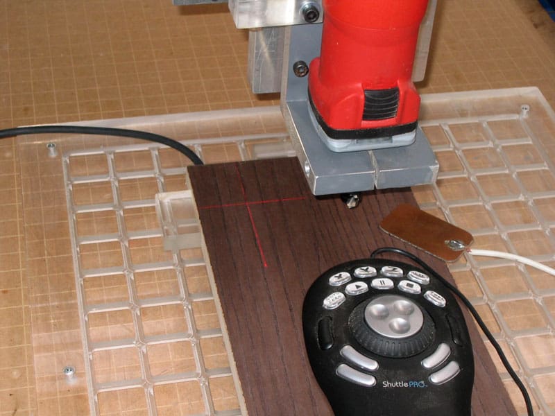 Red router table with grid pattern on surface and black control panel below red motor.