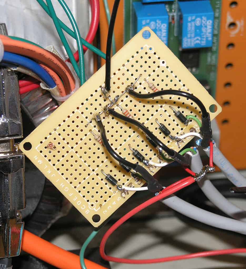 Yellow pegboard with electronic components and wires.