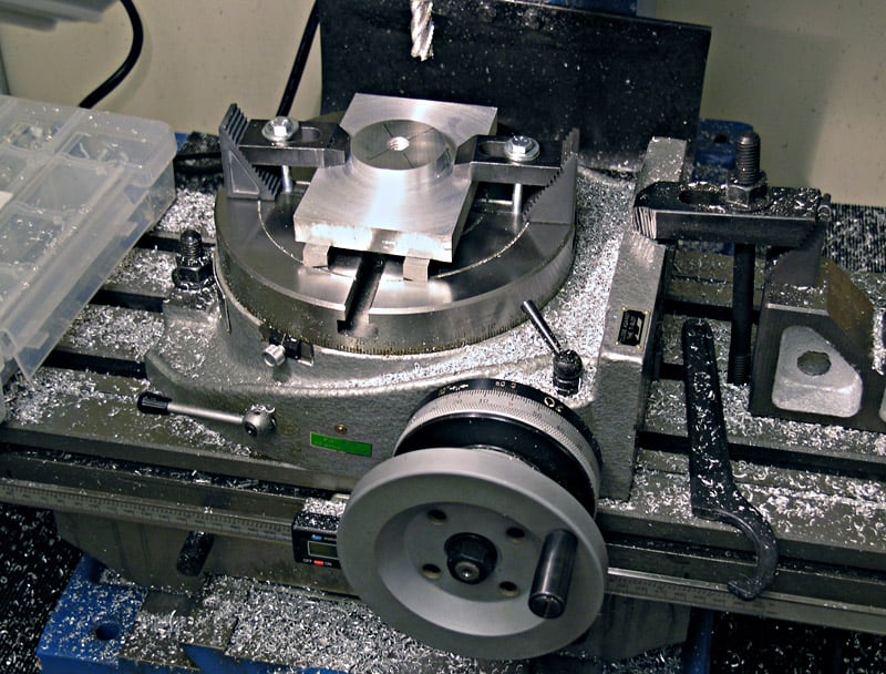 Metalworking lathe with metal shavings and dust, various tools and equipment.