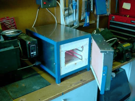 Small blue metal box on wooden workbench in well-lit room.