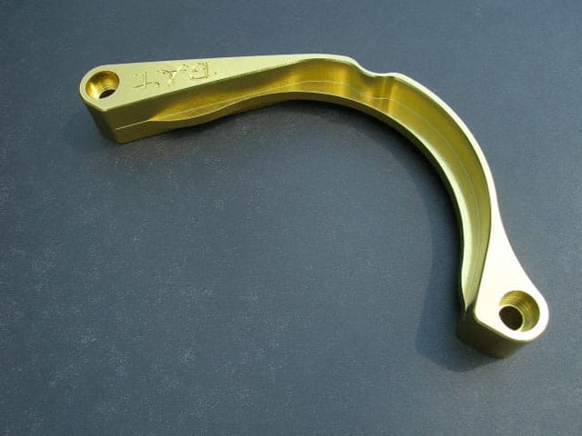 Gold-coloured metal component with hole and engraved text "EAT".