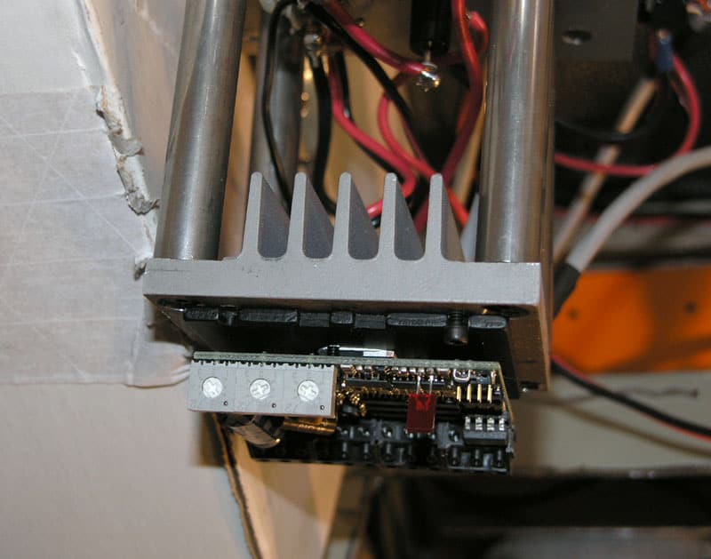 Gray metal component with wires and cables attached in a machine shop or fabrication setting.
