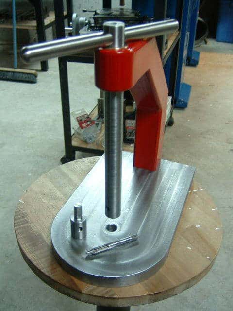 Red and silver tapping machine on wooden table.