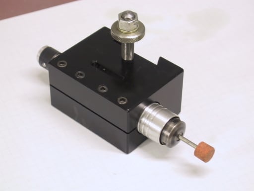 A small, black metal tool with a silver knob and copper-colored tip on a long rod.