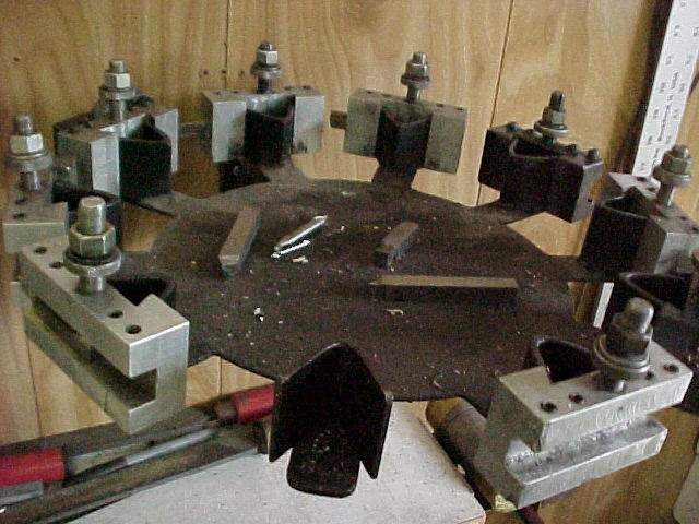 Metal parts and tools on a wooden workbench in a machine shop setting.