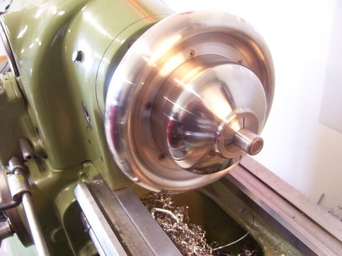 Older 3-jaw chuck with 5C collet mount on a lathe.