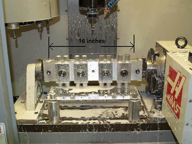 A 4-axis milling machine in a workshop setting, with mechanical components and precision mechanisms visible.