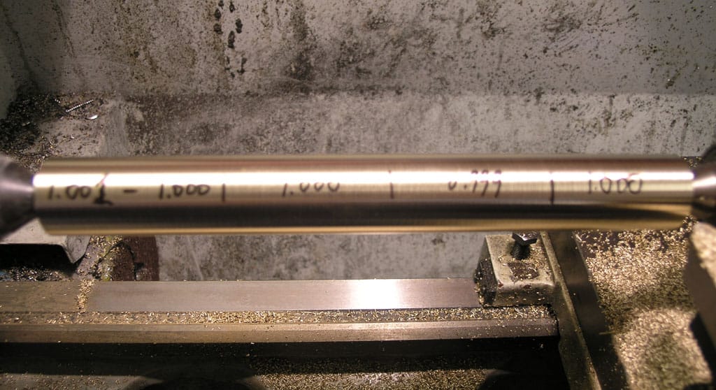 Metalworking machine shop with cylindrical objects on a lathe, handwritten measurements in black ink.