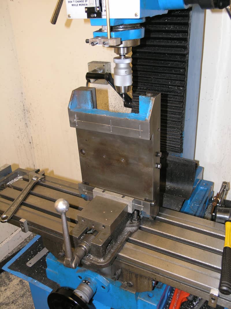 Blue milling machine with metal base plate and tools attached.