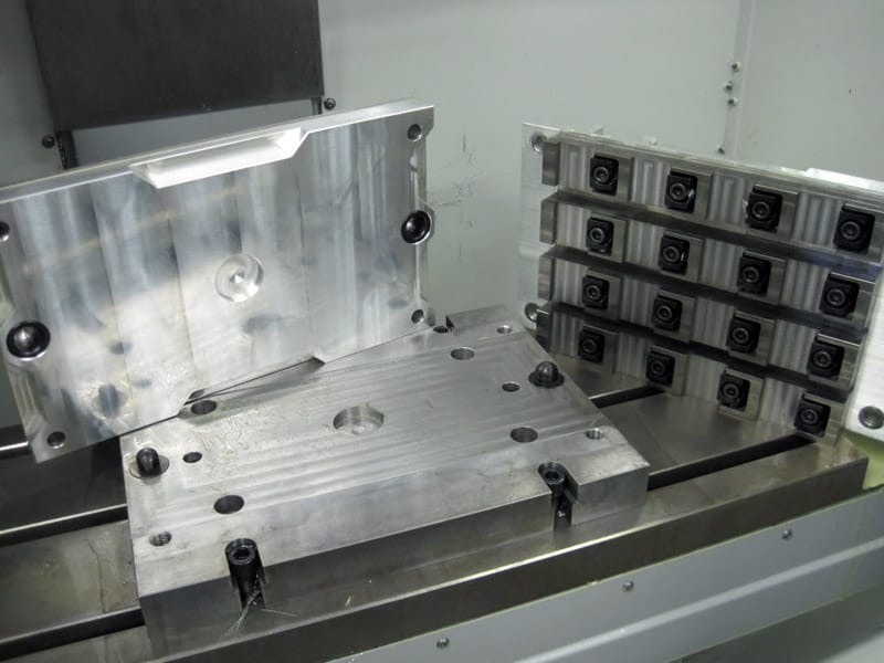 Metalwork pallet with plates, holes, and stacked metal blocks.