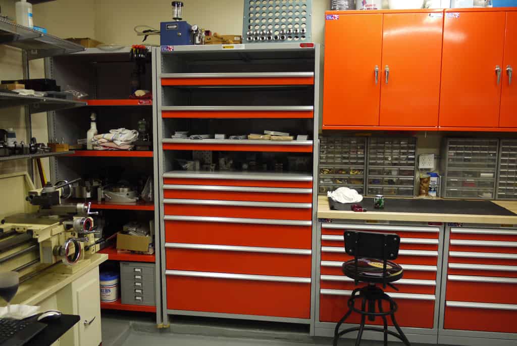Well-organized workshop with various machinery and tools on shelves and workbenches.