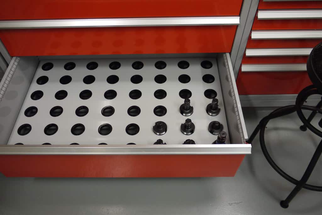 Red tool cabinet with open drawer, showing metal pieces on a white tray.
