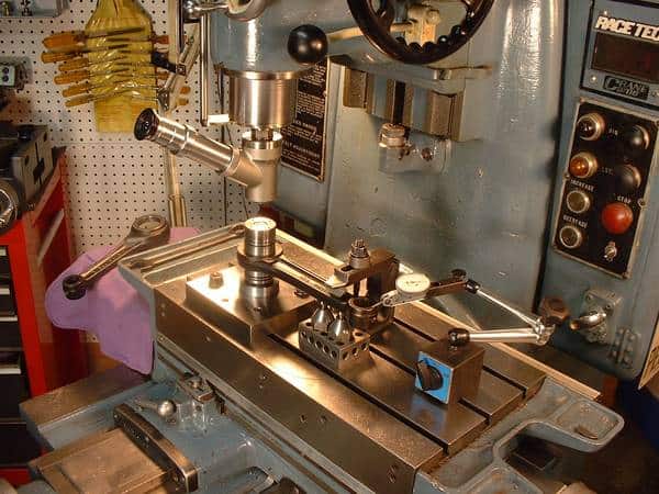 A stainless steel metalworking lathe in a workshop, surrounded by tools and machinery.