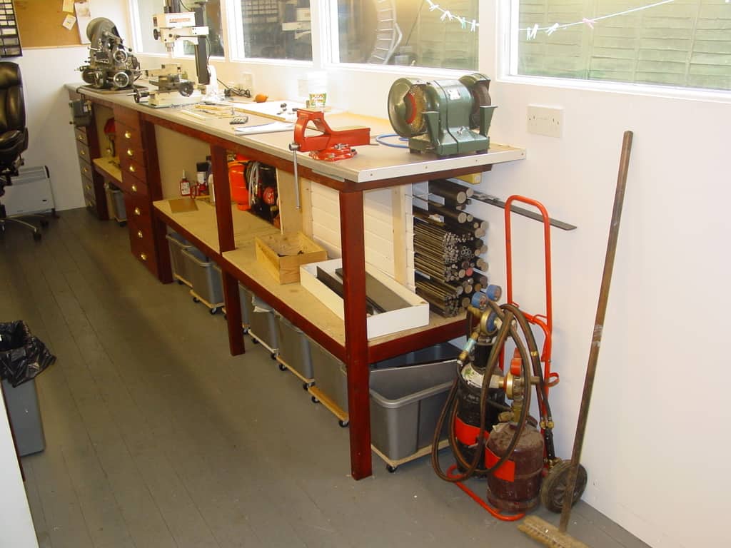 Organized workshop with workbench, tools, and metalworking machinery.