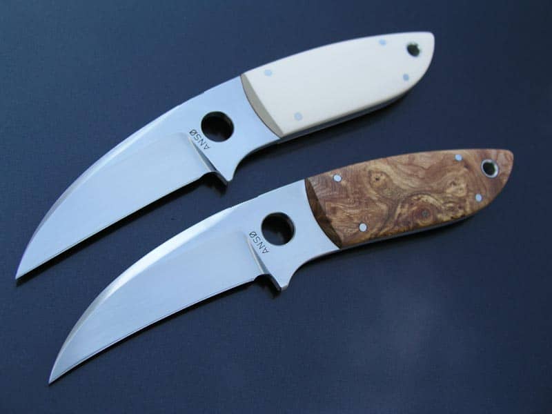 Two small knives with curved blades and pointed tips, polished finish.