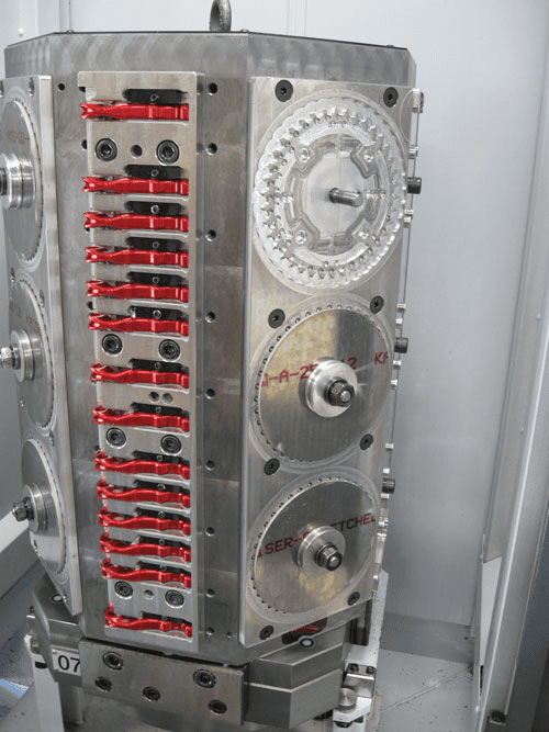 Large metal machine with red components and gears on a light gray background.