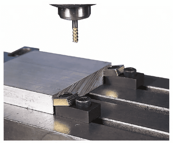 Close-up of a metalworking machine's cutting tool with silver metal body and threaded rod.