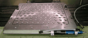 Metal surface with a grid of small holes and bolts.